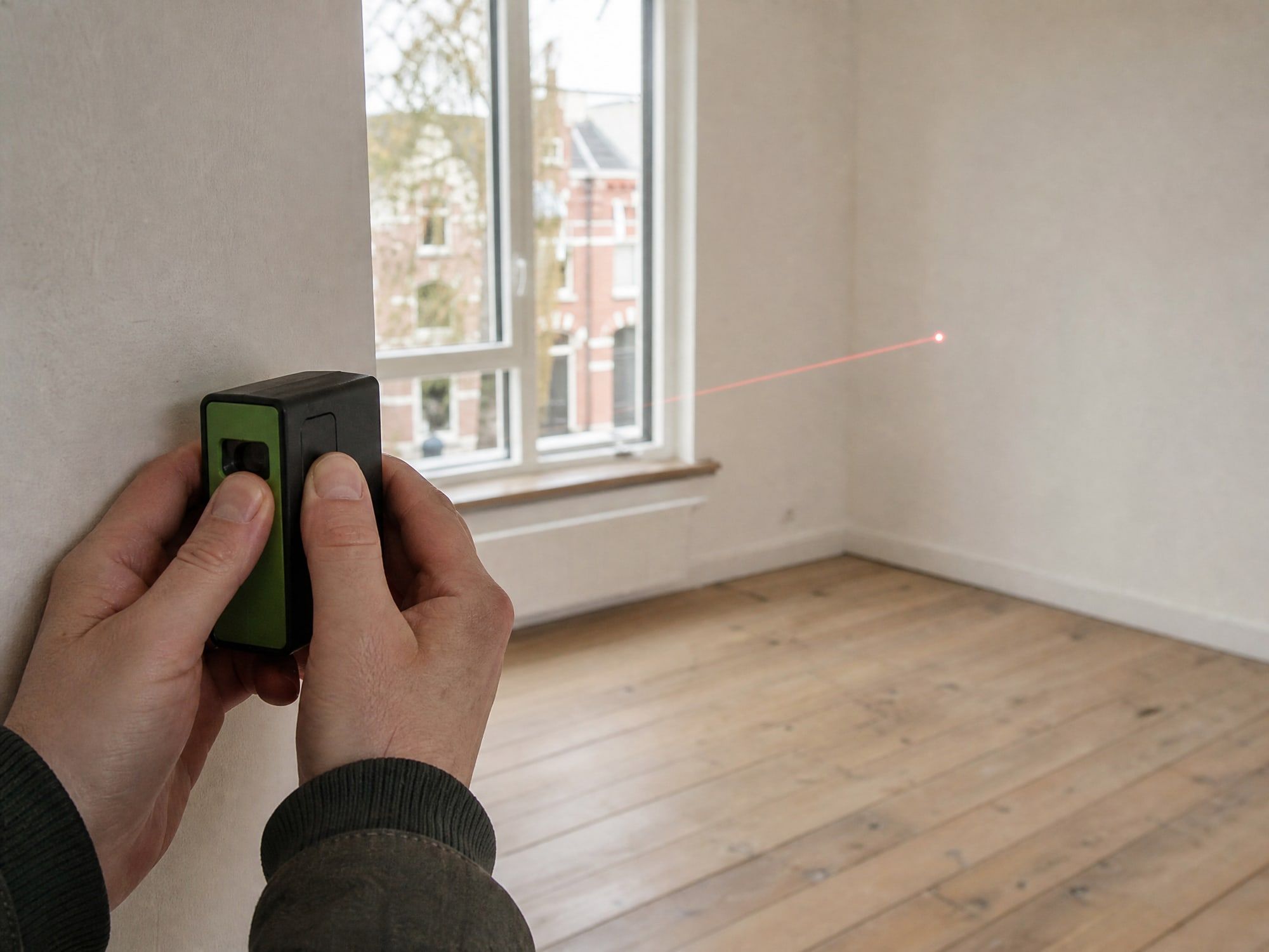 Adviseur meet een ruimte op met een laserafstandsmeter