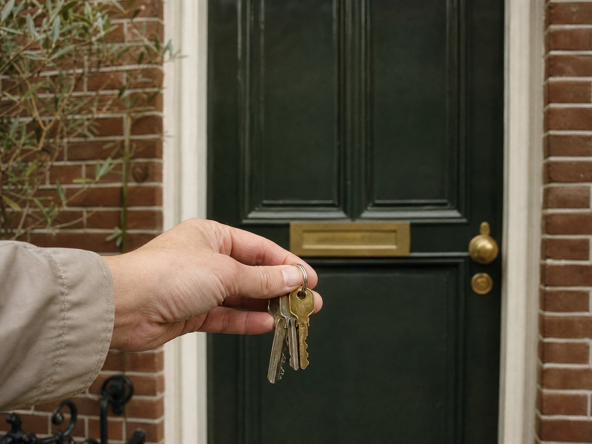 Hand met huissleutels voor een groene voordeur